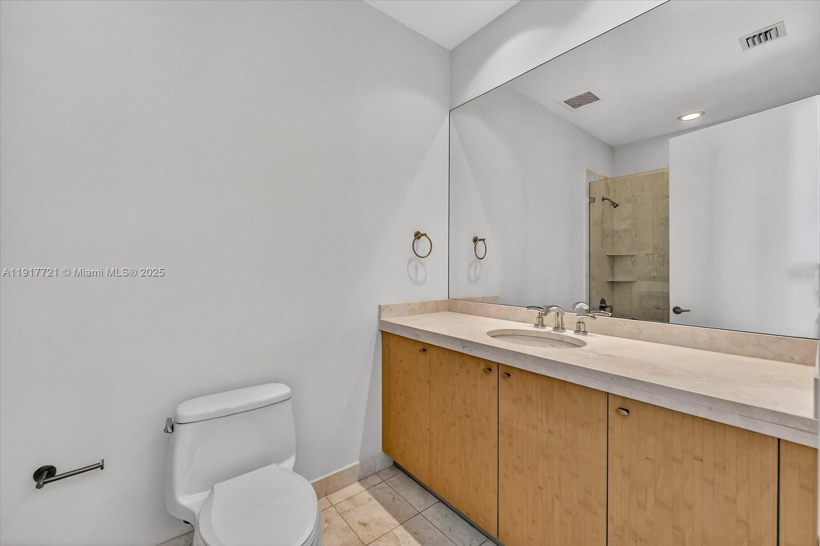 900 Brickell Key Boulevard, Unit 2304 Miami, FL 33131 - Photo 24 of 55 a bathroom with a granite countertop sink a large mirror and toilet