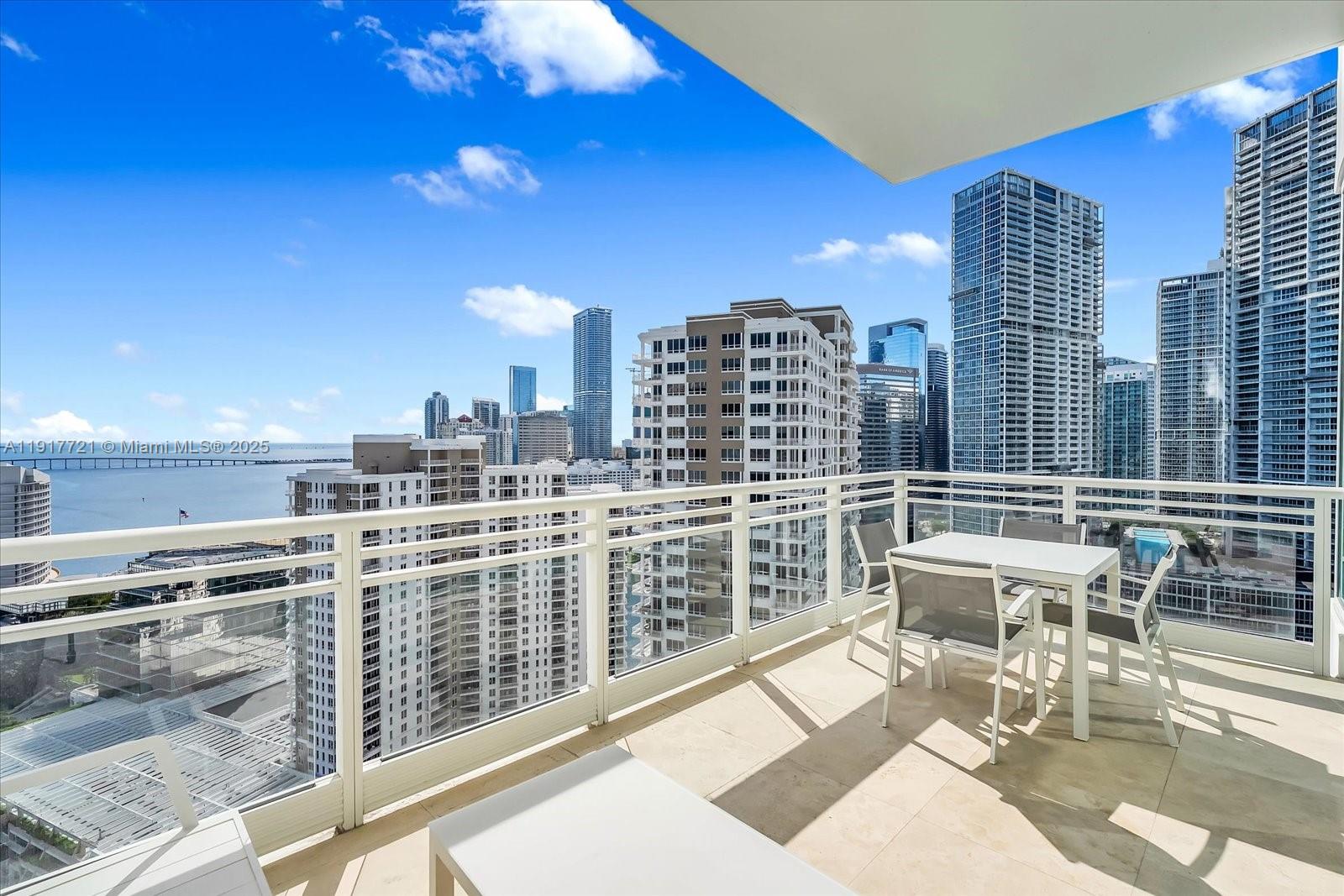 900 Brickell Key Boulevard, Unit 2304 Miami, FL 33131 - Photo 10 of 55 a view of a city from a balcony with dining table and chairs