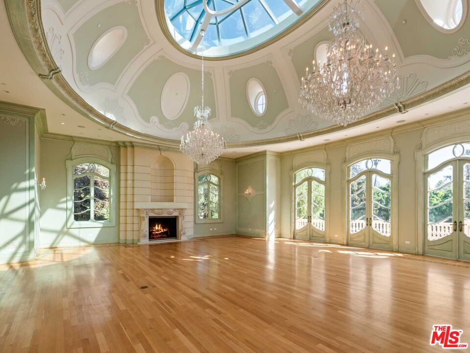 901 North Alpine Drive Beverly Hills, CA 90210 - Photo 15 of 33 an empty room with wooden floor fireplace and chandelier