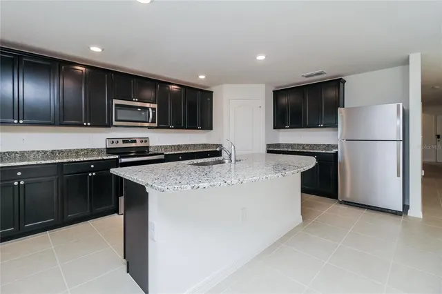 a kitchen with stainless steel appliances granite countertop a refrigerator stove a sink and a microwave