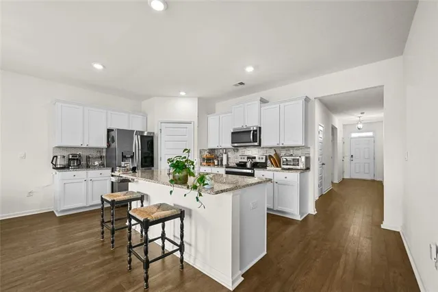 a kitchen with stainless steel appliances a refrigerator a stove top oven a sink dishwasher and white cabinets with wooden floor