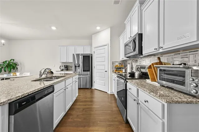 a large kitchen with stainless steel appliances granite countertop lots of counter space a sink and dishwasher a oven with wooden cabinets