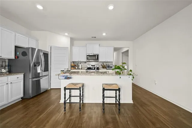 a kitchen with stainless steel appliances granite countertop a refrigerator a stove top oven a sink dishwasher and wooden floor