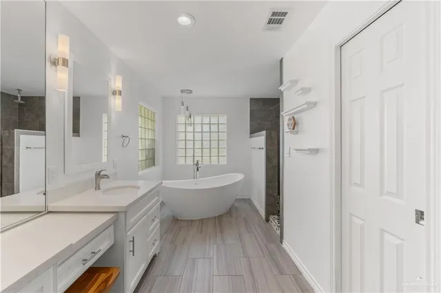 a spacious bathroom with a double vanity sink a mirror and a bathtub