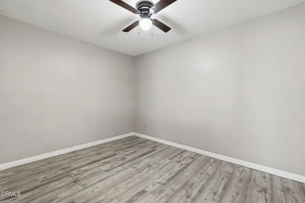 a view of a room with wooden floor and a ceiling fan