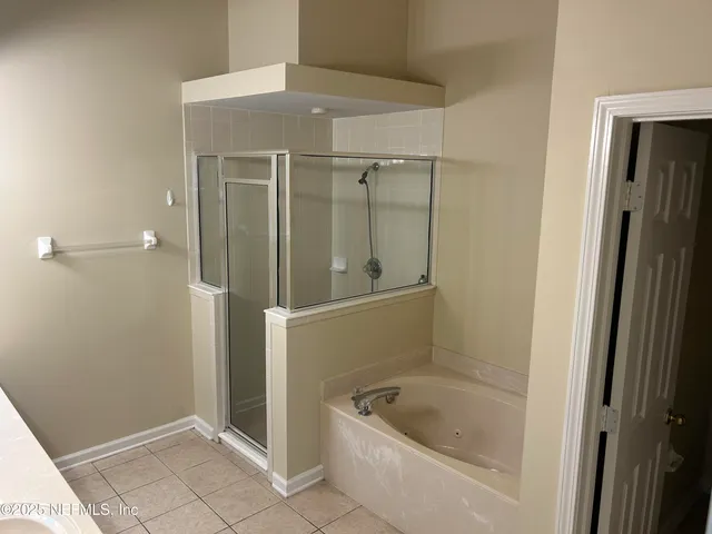 a bathroom with a tub a mirror and a shower