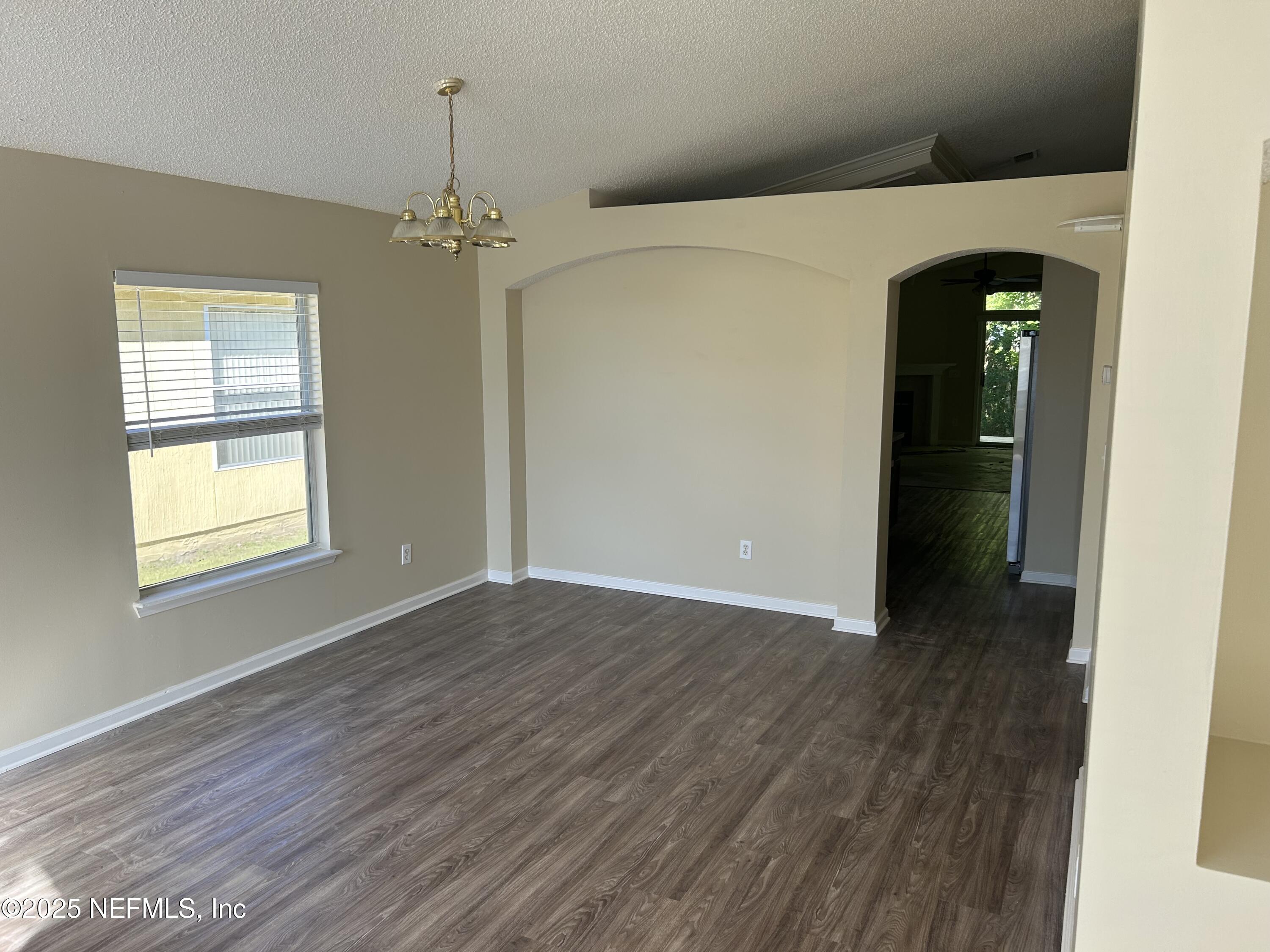 1425 Laurel Oak Drive Fleming Island, FL 32003 - Photo 6 of 25 an empty room with wooden floor chandelier and windows