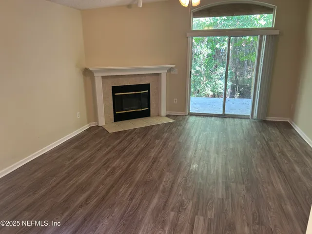 a view of empty room with wooden floor and fireplace