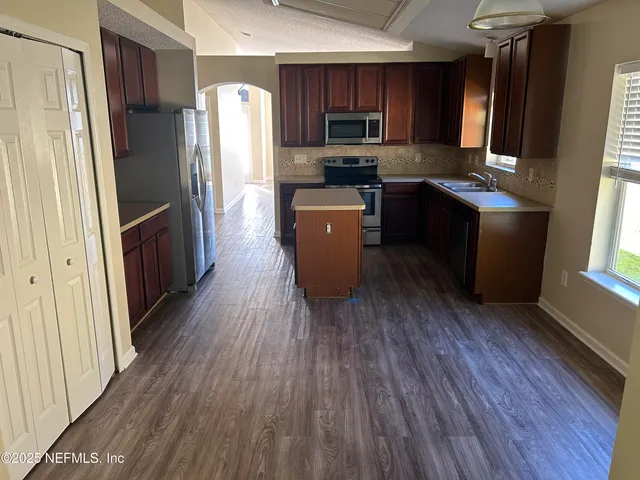 a kitchen with stainless steel appliances wooden floors and wooden cabinets