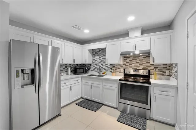 a kitchen with stainless steel appliances granite countertop a refrigerator and a stove top oven