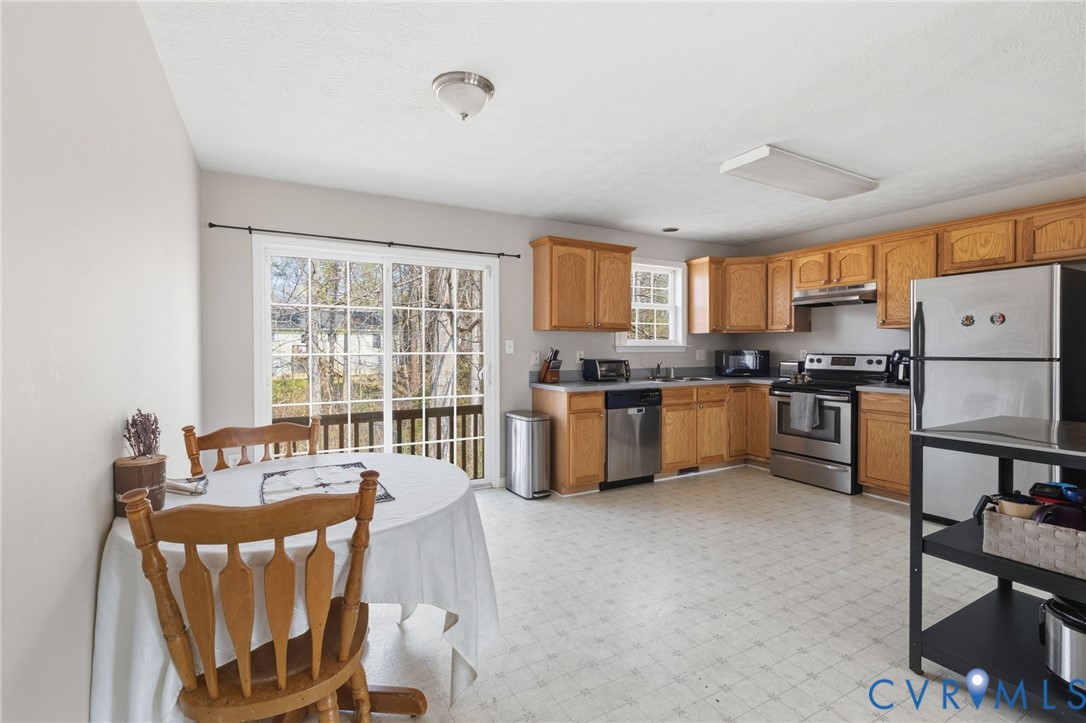 504 Gloucester Drive Ruther Glen, VA 22546 - Photo 5 of 28 a kitchen with granite countertop a stove a sink a dining table and chairs