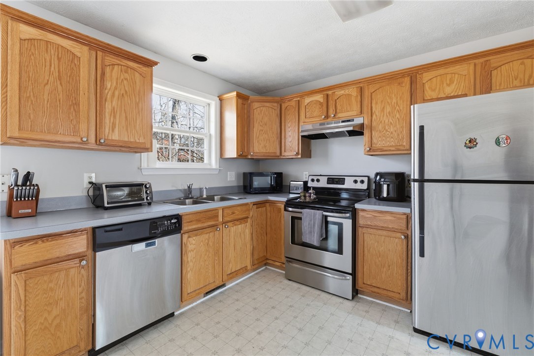 504 Gloucester Drive Ruther Glen, VA 22546 - Photo 9 of 28 a kitchen with stainless steel appliances granite countertop a refrigerator a sink dishwasher a stove and white countertops with wooden floor