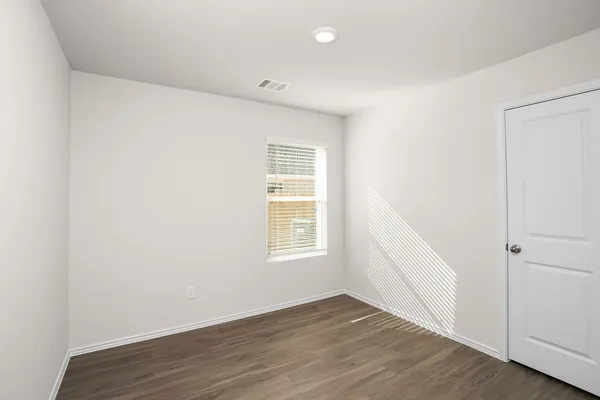 a view of an empty room with wooden floor and closet