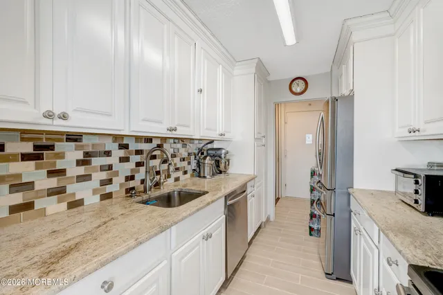 a kitchen with stainless steel appliances granite countertop a sink and a refrigerator