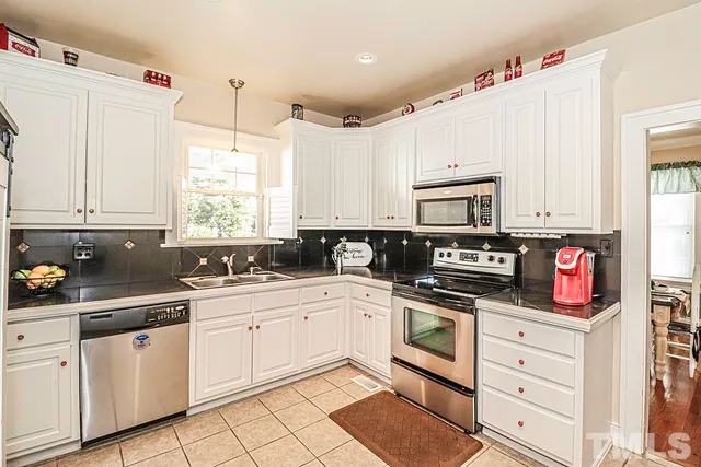 a kitchen with cabinets stainless steel appliances a sink and a window
