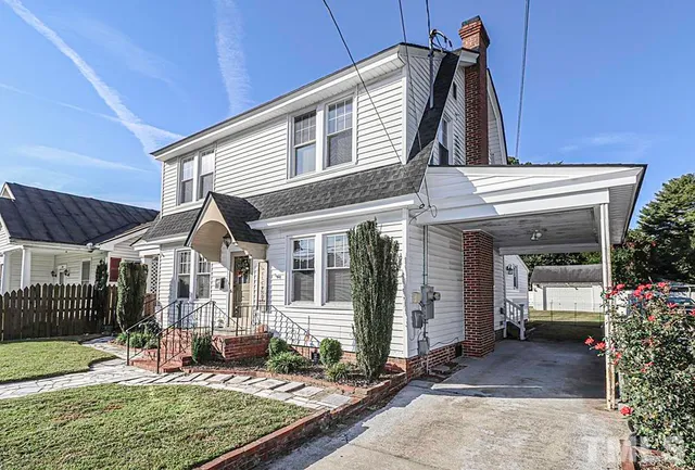a view of a house with porch next to a yard