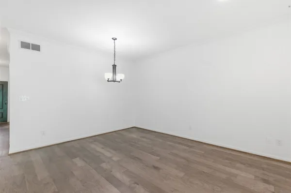 an empty room with wooden floor chandelier fan and windows