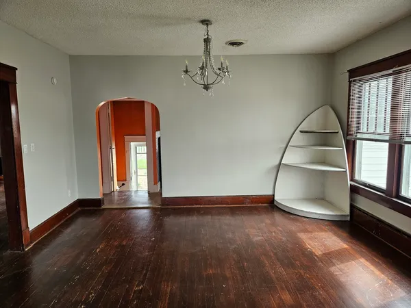 an empty room with wooden floor cabinet and windows