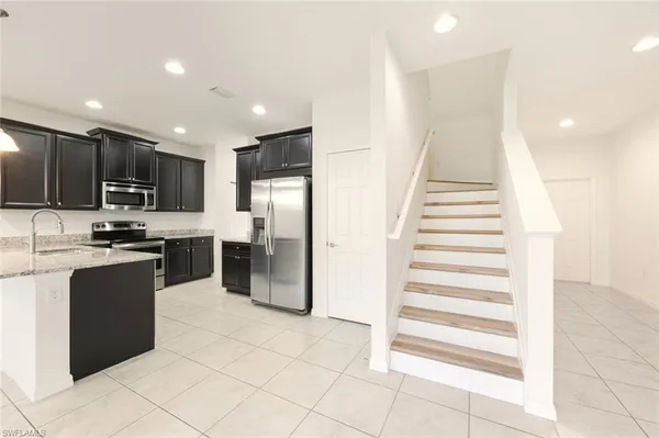 a view of a kitchen with kitchen island a sink appliances and a counter top space