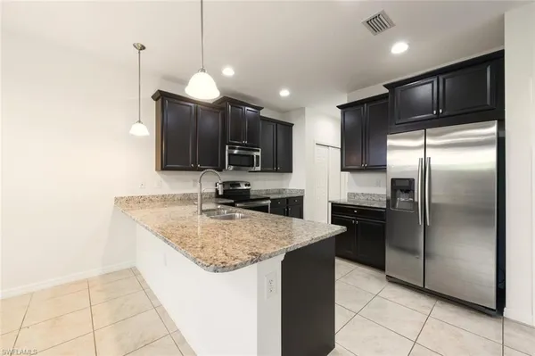 a kitchen with stainless steel appliances granite countertop a refrigerator and a sink