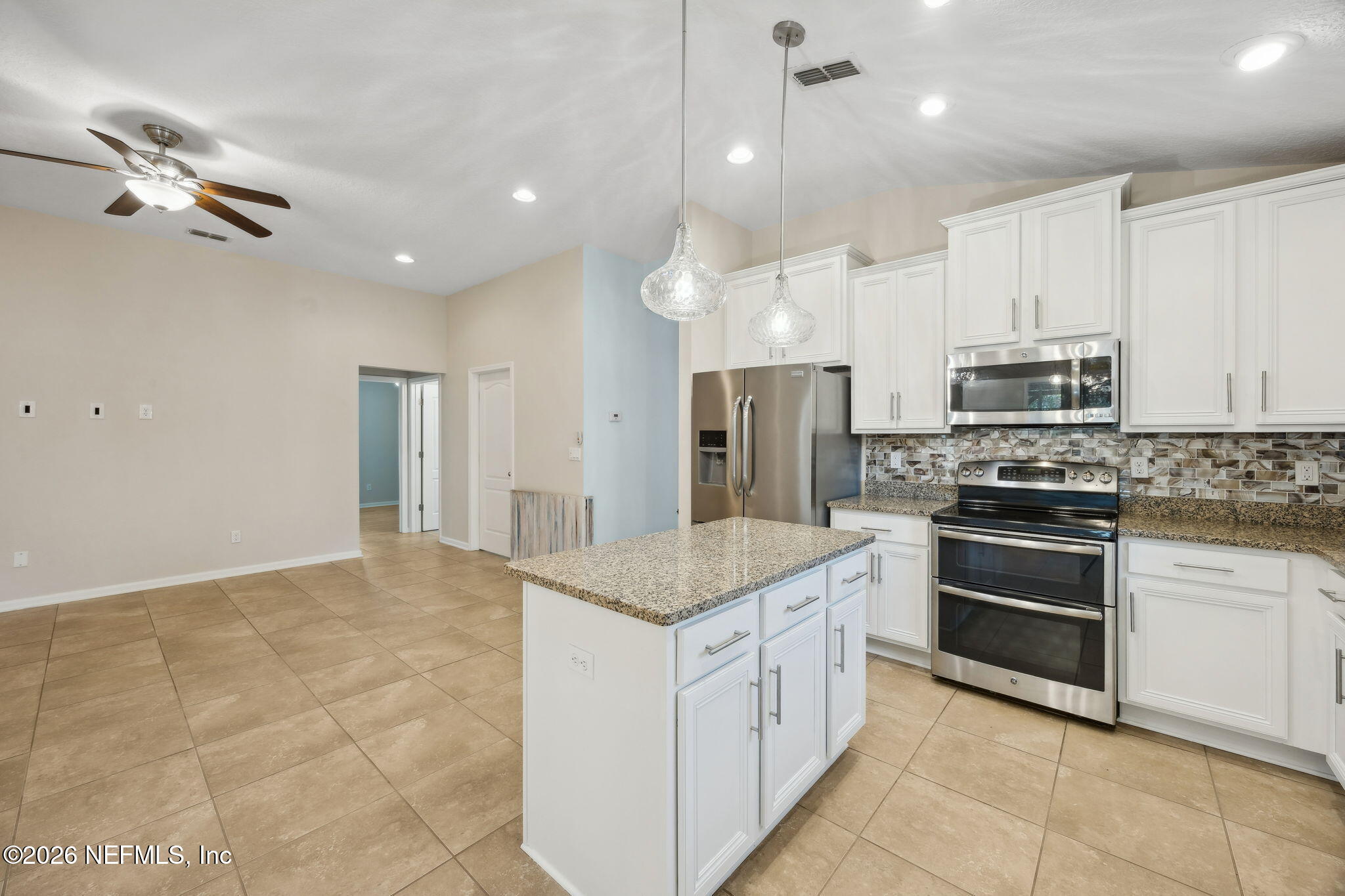 1602 Indigo Street Fernandina Beach, FL 32034 - Photo 16 of 35 a kitchen with stainless steel appliances granite countertop a stove oven and a refrigerator with white cabinets