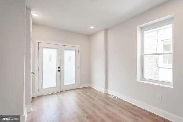 an empty room with wooden floor and windows