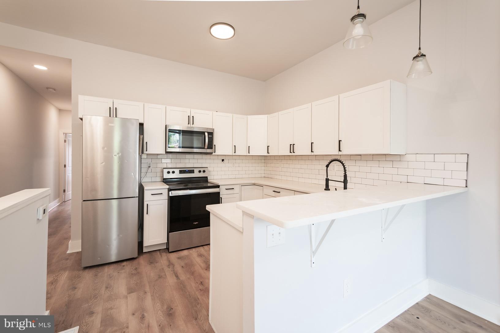5111 Willows Avenue, Unit B Philadelphia, PA 19143 - Photo 2 of 18 a kitchen with a sink a refrigerator a microwave and cabinets