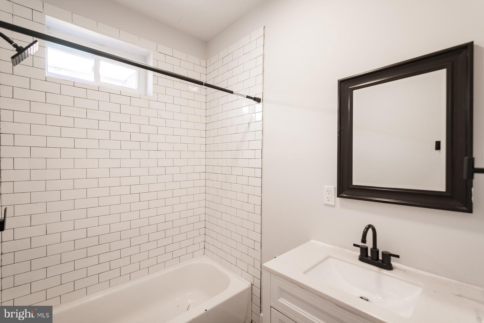 5111 Willows Avenue, Unit B Philadelphia, PA 19143 - Photo 7 of 18 a bathroom with a sink a mirror and a bathtub