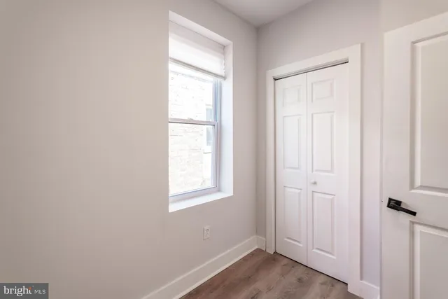 an empty room with wooden floor closet and windows