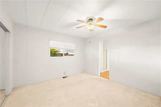 an empty room with a window and a fan