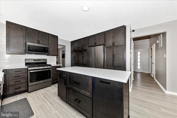 a kitchen with a refrigerator stove and wooden floor