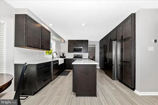 a kitchen with stainless steel appliances wooden cabinets a stove top oven a refrigerator with island and chairs