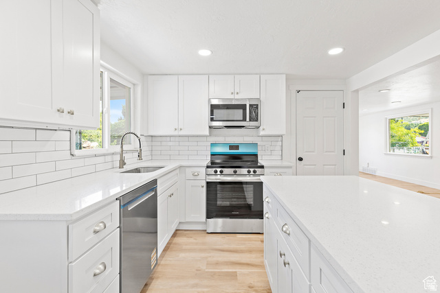 372 East 400 North Springville, UT 84663 - Photo 10 of 27 White cabinetry, stainless steel appliances, white subway tile backsplash, white countertops, and wood-finish flooring