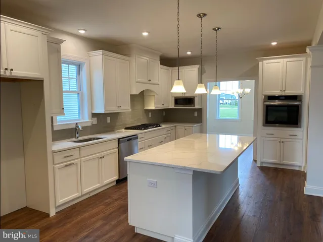 a large kitchen with stainless steel appliances kitchen island granite countertop a stove a sink and a wooden floor