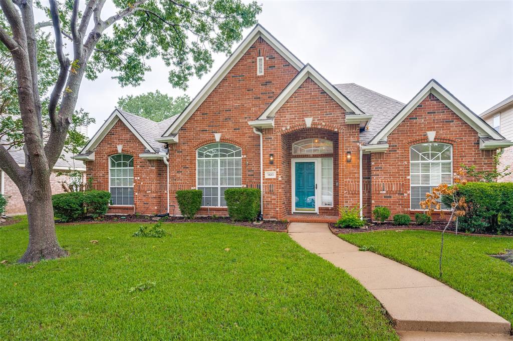 Traditional-style home featuring brick siding, a front yard, and roof with shingles