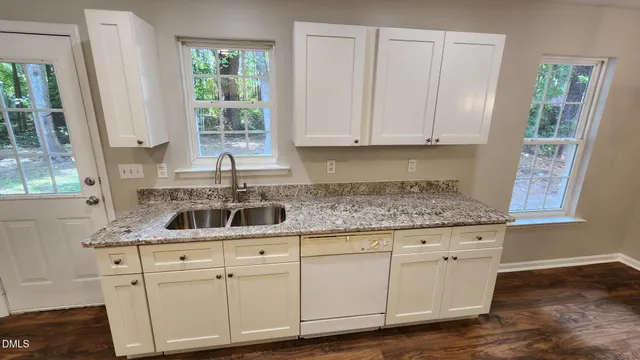 a kitchen with white cabinets and window
