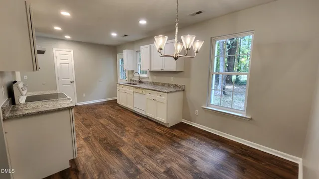 a large kitchen with cabinets wooden floor and stainless steel appliances