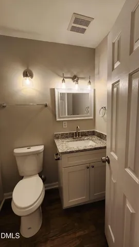 a bathroom with a granite countertop toilet a sink and a mirror