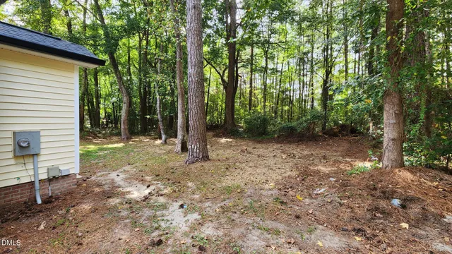 a backyard of a house with lots of plants and large trees