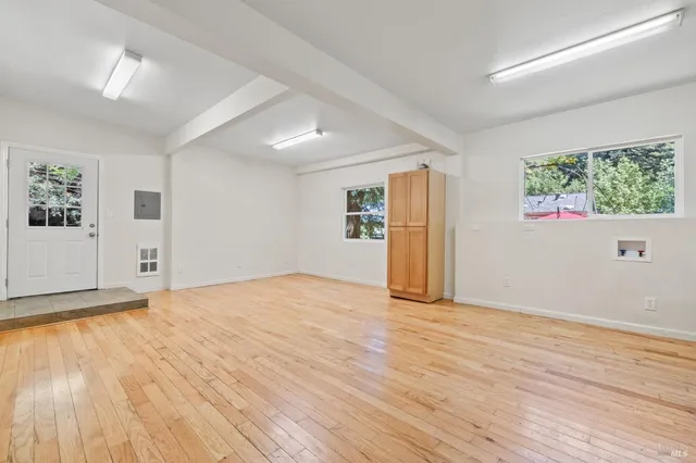a view of empty room with wooden floor and fan