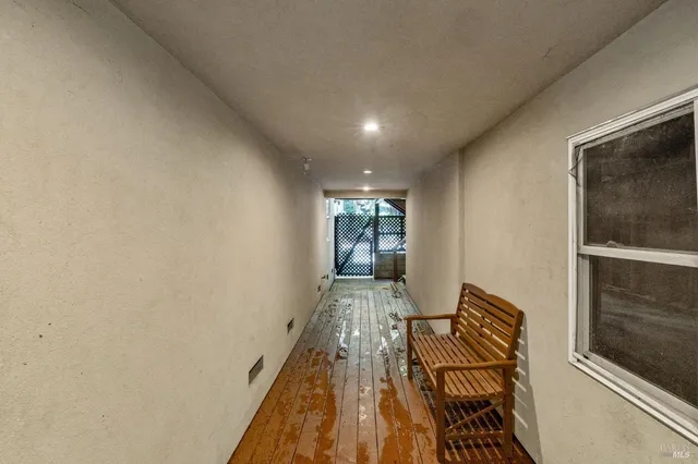 a view of a hallway with wooden floor and a bathroom