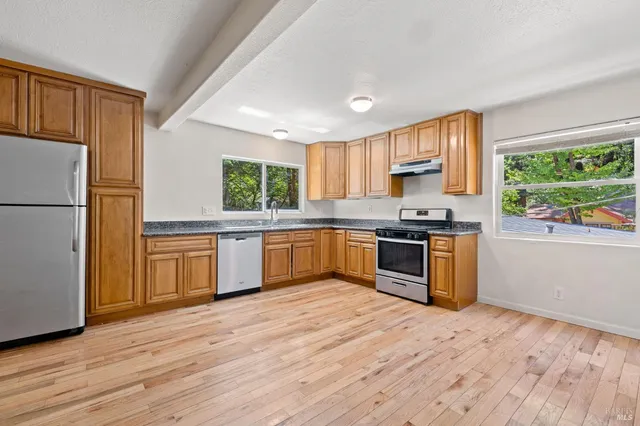 a kitchen with granite countertop a refrigerator cabinets wooden floor and a window