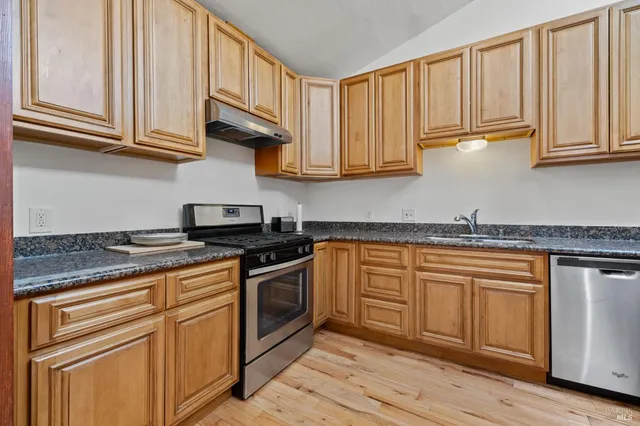 a kitchen with stainless steel appliances granite countertop a stove a sink and a microwave