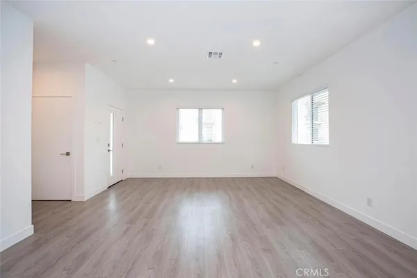 an empty room with wooden floor and windows