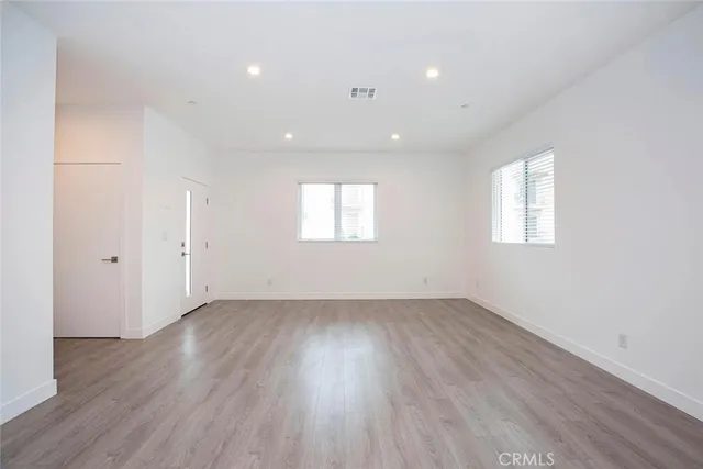 an empty room with wooden floor and windows