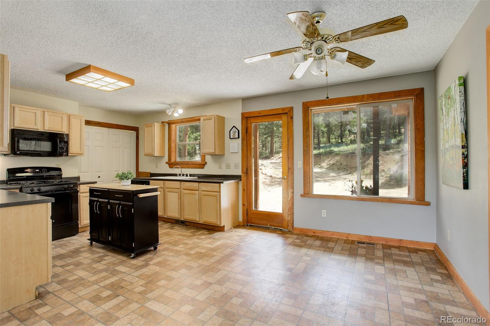 307 Hitchrack Road Bailey, CO 80421 - Photo 8 of 30 a large kitchen with kitchen island granite countertop a stove top oven a sink a counter space and cabinets