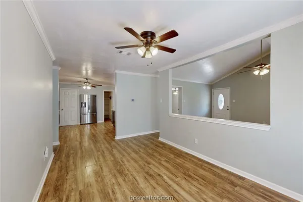 a view of an empty room with window and wooden floor