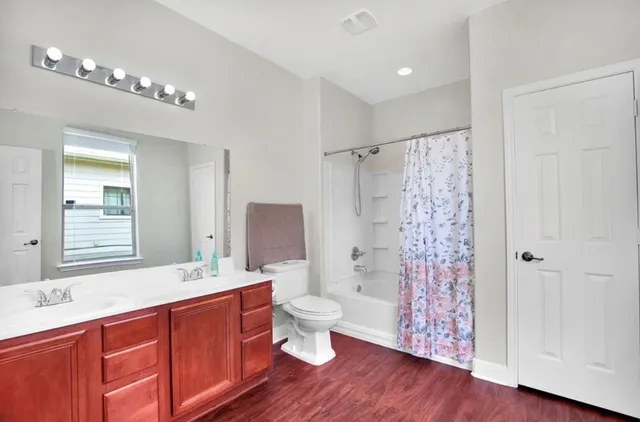 a spacious bathroom with a double vanity sink toilet mirror and shower