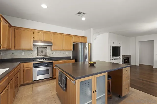 a kitchen with a stove a sink a counter top space and living room view