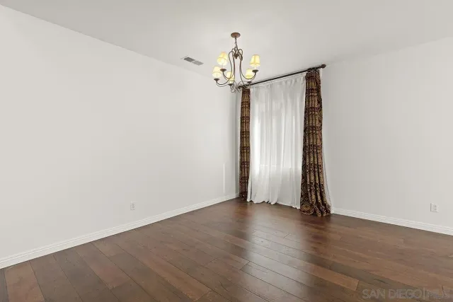 a view of an empty room with wooden floor and stairs